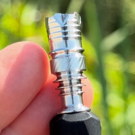 Close-up of the stainless steel DynaVap B2 tip showing redesigned grooves and improved geometry against a natural green background.