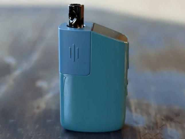 Teal Fury 3 dry herb vaporizer standing upright on a wood surface, showcasing its compact and stylish design.