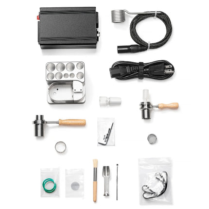Wireless One Hit Wonder V2 titanium kit components laid out on a table, including ruby-filled heater head, aluminum dock, PID controller, Matrix titanium bowl, diffuser adapters, coil, and accessories