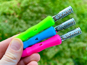 Holding green, blue and pink Dynavap B Portable Vaporizer.