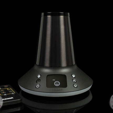 Arizer XQ2 desktop vaporizer on black background with remote control next to it.