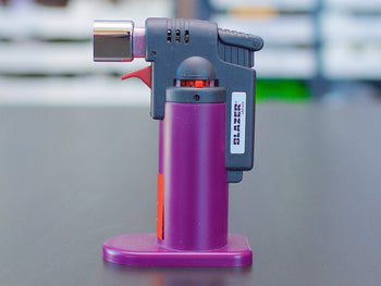 Purple Blazer Firefox Butane Torch lighter standing on a table.