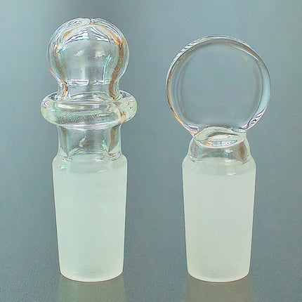 Round top and flat top 14mm glass stopper on a table.