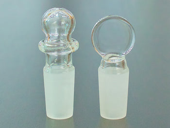 Round top and flat top 14mm glass stopper on a table.