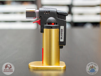 Gold Blazer Firefox Butane Torch lighter standing on a table.